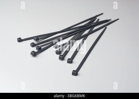 black plastic cable or zip ties scattered on gray background, fasteners use to bundle cables or wires together, soft focus with copy space Stock Photo