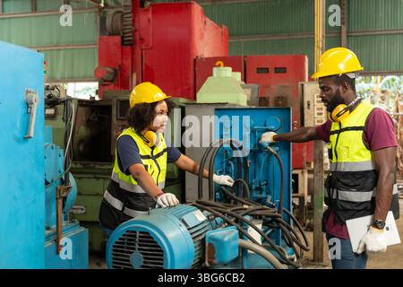 professional engineer worker male help assisting young women worker to check service old machine in heavy industry plant Stock Photo