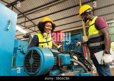 professional engineer worker male help assisting young women worker to check service old machine in heavy industry plant Stock Photo