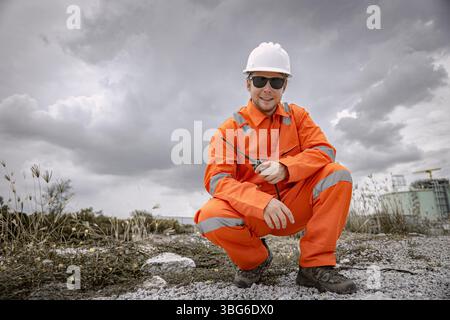 Portrait professional happy smiling Petroleum Caucasian male worker with LNG natural gas tank background dramatic cloudy sky Stock Photo