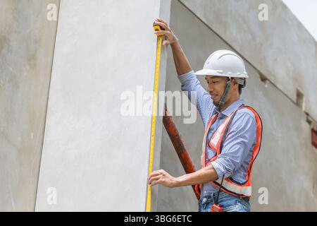 Home builder worker using tape measurement working in house building construction site Stock Photo
