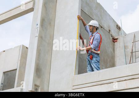 Home builder worker using tape measurement working in house building construction site Stock Photo