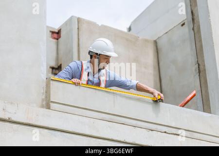 Home builder worker using tape measurement working in house building construction site Stock Photo