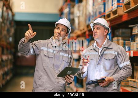 Caucasian smart American male team working in warehouse using the tablet for stock checking and inspection the boxes, logistic warehouse to deliver th Stock Photo