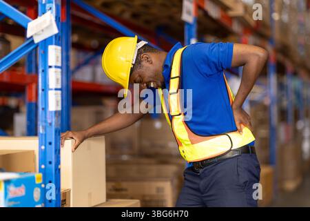 worker back pain, african male employee worker working in warehouse storage suffering from health muscle problem Stock Photo