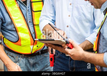 Professional construction engineer workers team working cooperate together consulting looking at tablet screen at project building construction site. Stock Photo