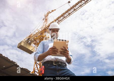 Hispanic Indian professional construction engineer working control operate Crane hoist in construction site Stock Photo