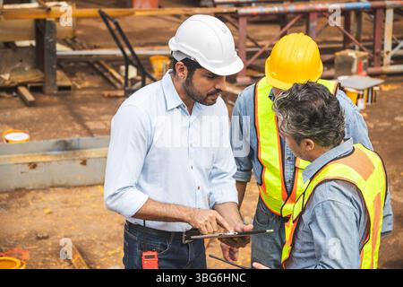 Construction engineer team working together join teamwork talking together at construction site planning project with on tablet computer Stock Photo