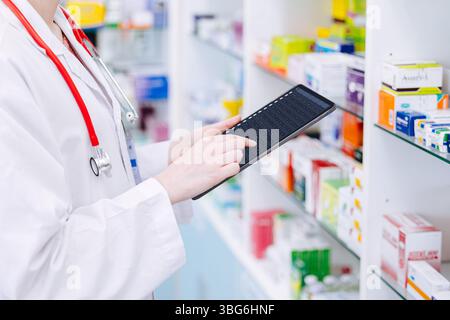 Pharmacist working, Druggist doctor using tablet computer to check drug shelf life detail in stock with smart device online database Stock Photo