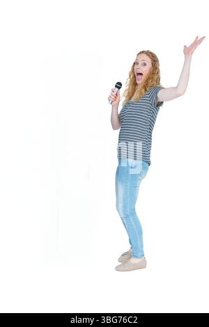 Woman standing in studio wearing striped shirt holding handheld mic, raising arm, copy space Stock Photo