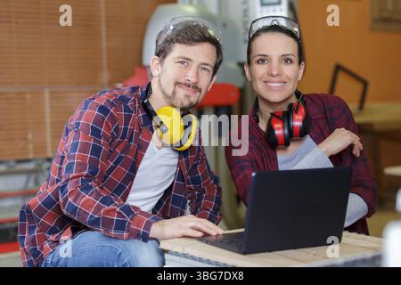 young couple with laptop in the carpenter workroom Stock Photo