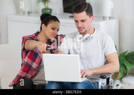 disabled man using laptop sitting next to his girlfriend Stock Photo