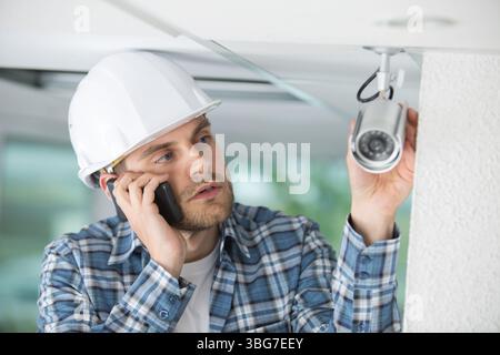 contractor talking on telephone by cctv camera Stock Photo
