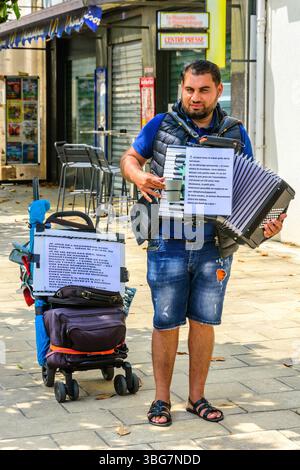 Busker playing a piano accordion in a town center - central FRance. Stock Photo