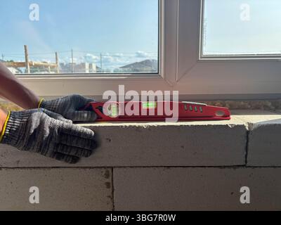 A building level on a window sill during house construction. The builder checks the level of the window sill. Construction and renovation of housing. Stock Photo