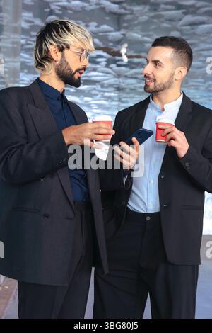 Vertical image of two businessmen drinking coffee and chatting in office setting Stock Photo