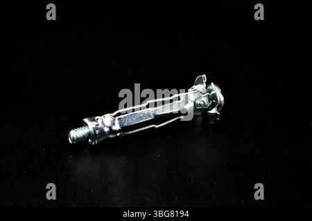 Anchor bolt for working with plasterboard, side view, lies on a black background. Stock Photo