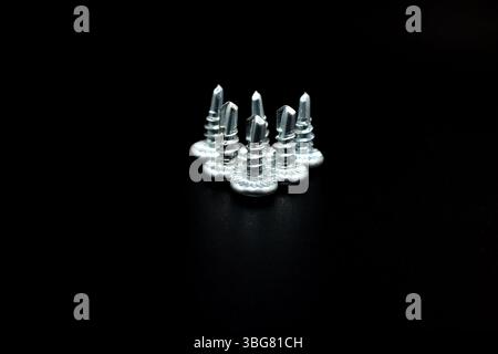 Short self-tapping screws for metal stand on a black background Stock Photo