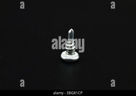 Short self-tapping screw for metal on a black background Stock Photo