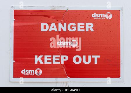 Close up of a red sign reading Danger, Keep Out with logos for the Birmingham based demolition company DSM in UK. Stock Photo