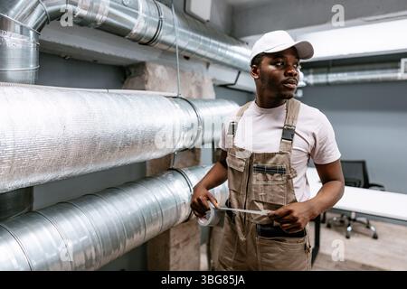 Professional worker performs maintenance on ventilation systems in a modern office setting during the day Stock Photo