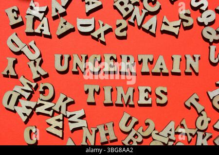 Uncertain Times, words in on red background surrounded by random letters as banner headline Stock Photo