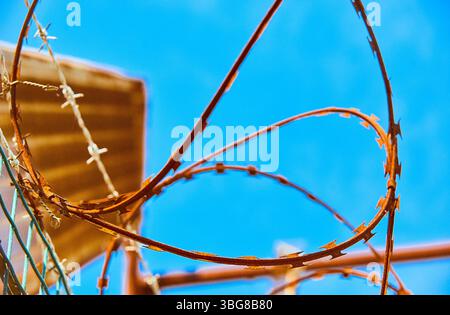 Rusty razor wire against blue sky Stock Photo