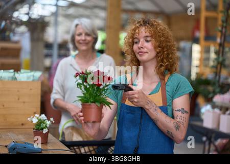 Florist scanning red carnation pot in flower shop Stock Photo