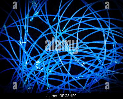 abstract arrangement of blue lighted or lit LED lights on  wires curled up on a black background Stock Photo