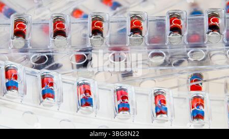 Closeup of SMD Zener diodes packaged in plastic blister pack strips on a white background. Pile of red electronic components in transparent packaging. Stock Photo