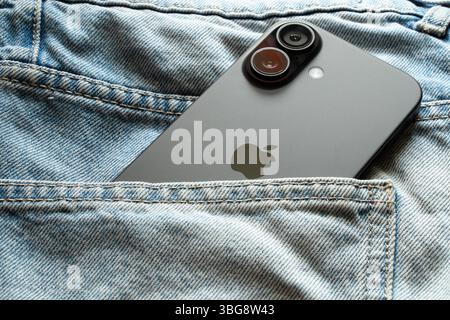 Ukraine Dnipro 04-06-2025 Apple iPhone 16 lies in the pocket of jeans, modern gadgets in the light on clothes Stock Photo