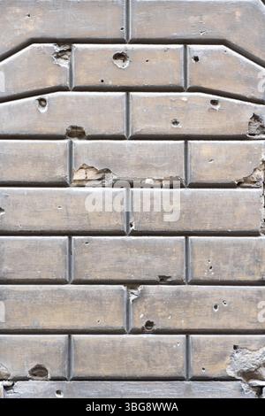 Fragment of an old brick wall with characteristic bullet and shell potholes, chips, cracks and holes. The texture of the worn surface with the histori Stock Photo