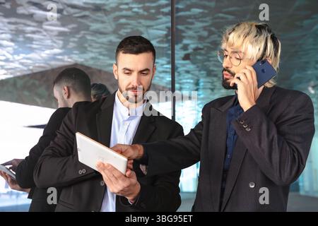 Businessmen working together with tablet and phone in modern glass office Stock Photo