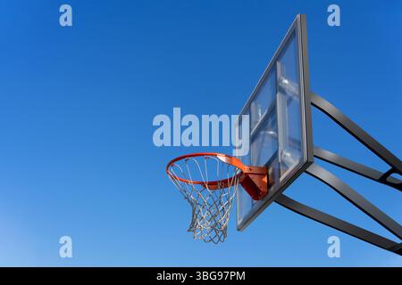 A outdoor basketball net on a clear backboard with a blue sky background Stock Photo