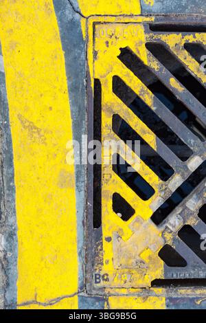 A weathered yellow and gray drainage grate, showcasing the texture and rust of urban infrastructure in Dubai. Stock Photo