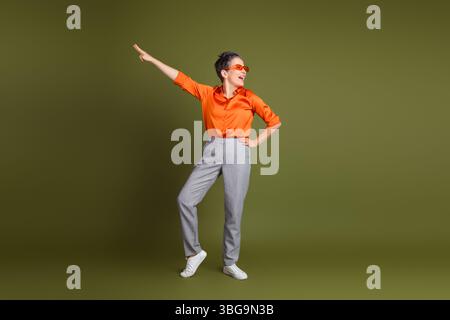 Confident woman in casual attire posing joyfully against a khaki background showcasing style and personality Stock Photo