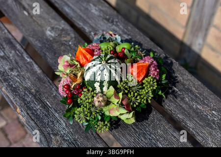 Seasonal floral wreath with acorns, berries, and orange flowers placed on elegant table setting. Stock Photo