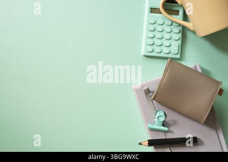 Notebook, calculator, clip, mug cup, pouch on green desk background. flat lay, top view. workspace Stock Photo