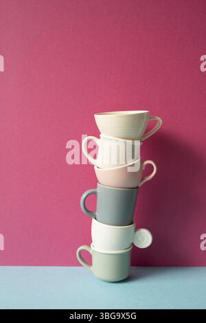 Stack of colorful coffee cups on skyblue table. pink wall background Stock Photo