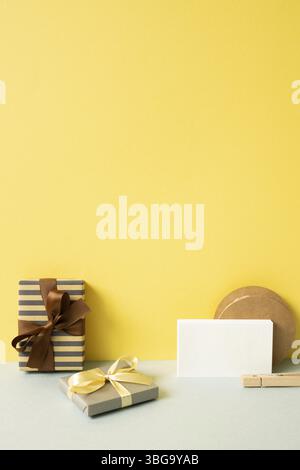 Gift boxes and wrapping accessory on gray desk. yellow wall background Stock Photo