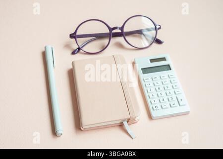 Diary notebook, pen, eyeglasses, calculator on pink desk background Stock Photo