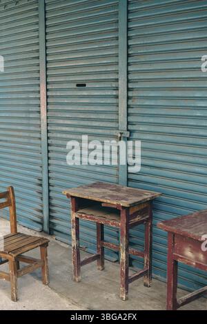 Abandoned wooden desk and chair in front of blue shutter door in Taiwan Stock Photo