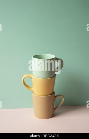 Stack of mug cup on pink table. mint green wall background Stock Photo