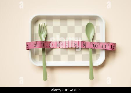 Empty tray plate and fork, spoon with tape measure on pink table background. healthy diet body weight control concept Stock Photo