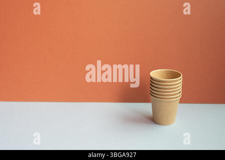 Disposable kraft paper cups on gray table. red wall background Stock Photo