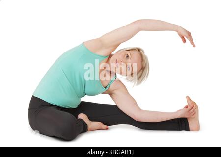 Full body view of a young blond woman doing yoga exercises in front of white background with gentle shadow Stock Photo