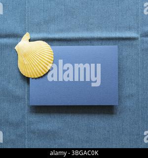 Blank memo paper with summer marine seashell on blue fabric background. top view, copy space Stock Photo