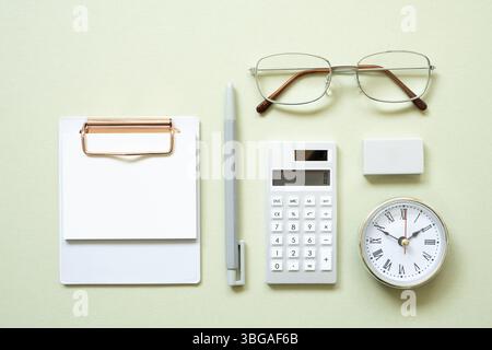 Clipboard, pen, clock, eyeglasses, calculator, eraser on mint desk background. study and workspace. flat lay, top view, copy space Stock Photo