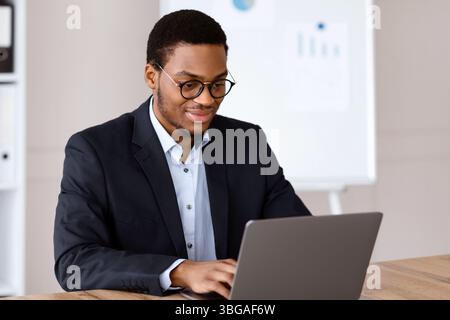 Young black entrepreneur working with laptop, office interior Stock Photo