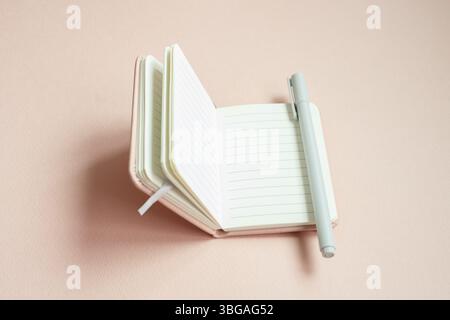 Open lined notebook and pen on pink desk background Stock Photo